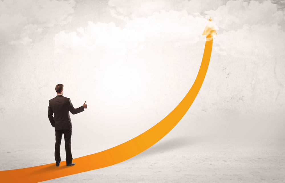 A young adult salesman standing on a big orange arrow pointing up in a bright empty space concept A young adult salesman standing on a big orange arrow pointing up in a bright empty space concept